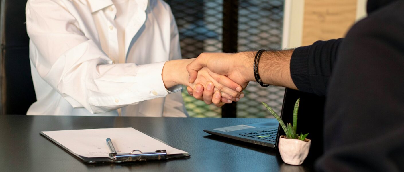 a man and a woman shaking hands in front of a laptop