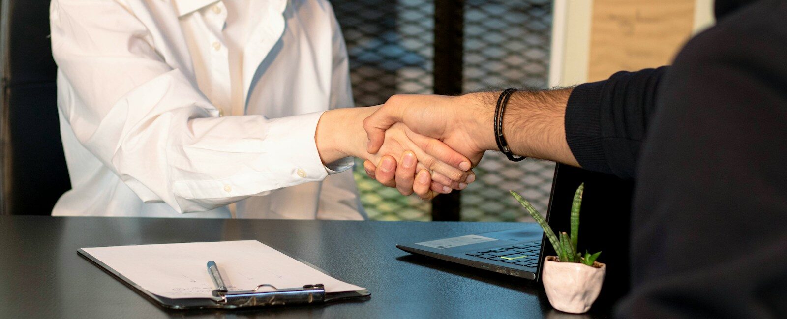 a man and a woman shaking hands in front of a laptop